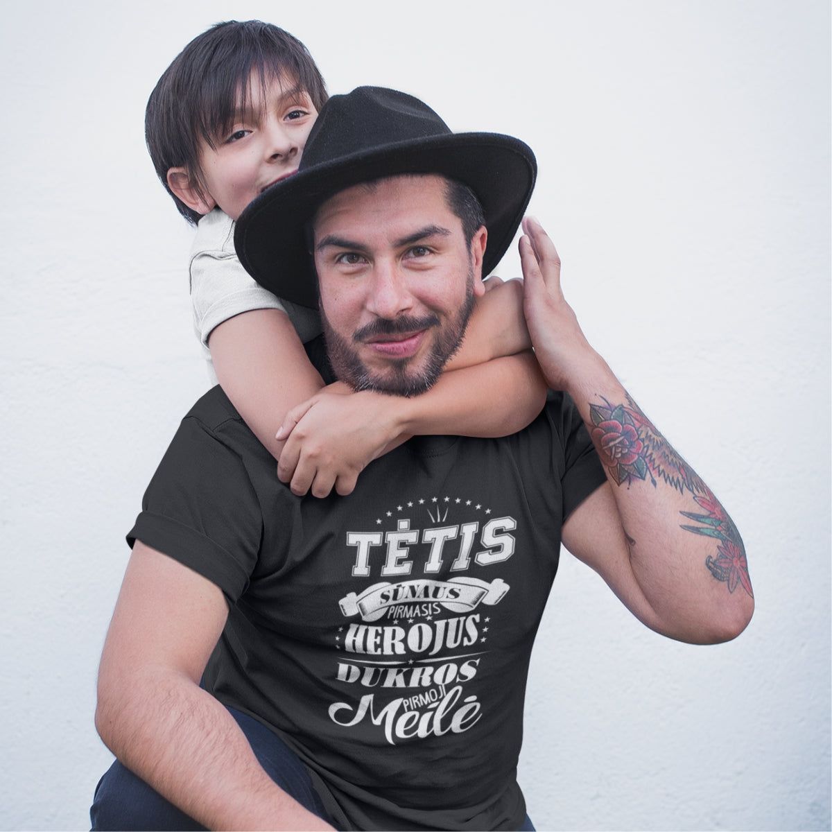 Juodi marškinėliai su baltu užrašu "Tėtis herojus ir pirmoji meilė"
